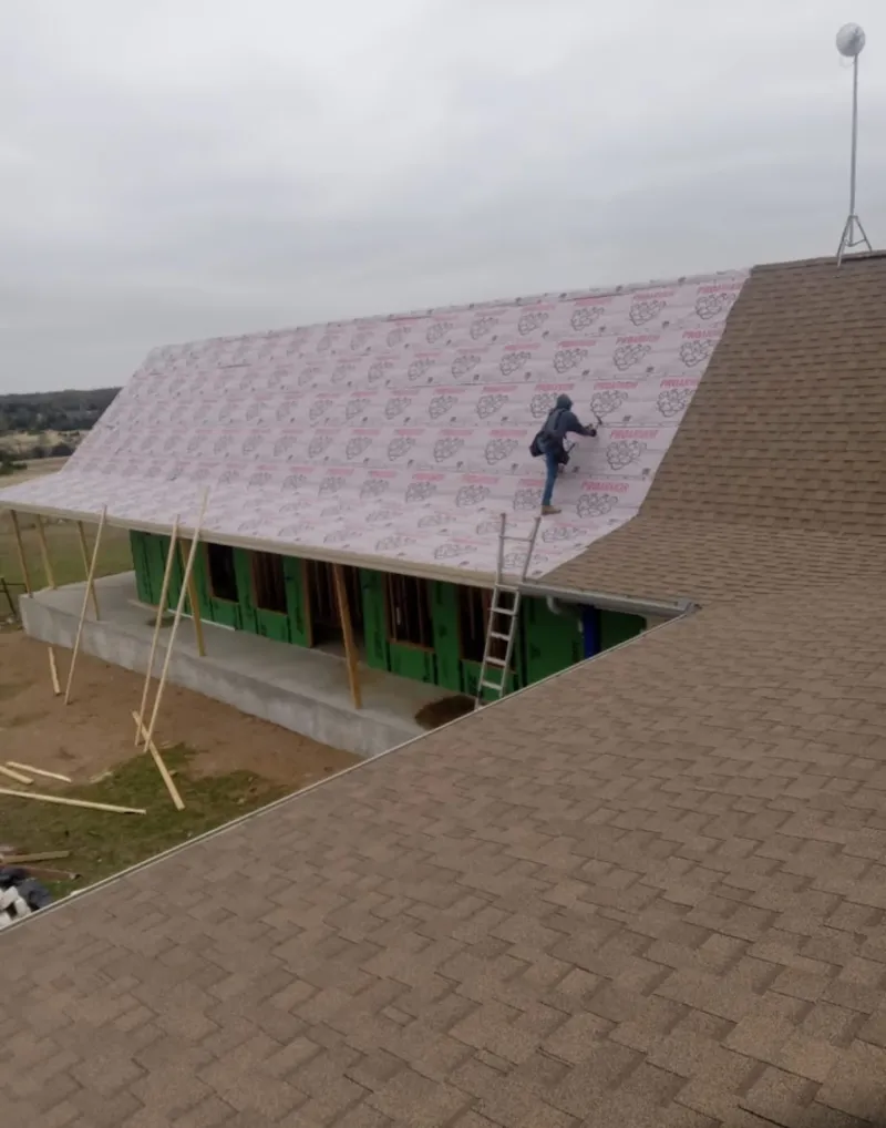 Worker preparing underlayment for a metal roof installation in Littleton